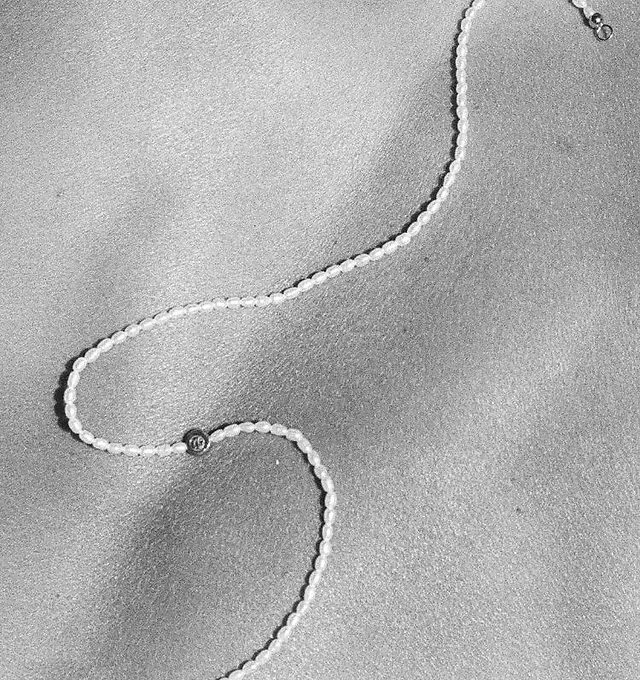 Feine Perlenkette auf Sand, Schwarz-Weiß-Aufnahme
